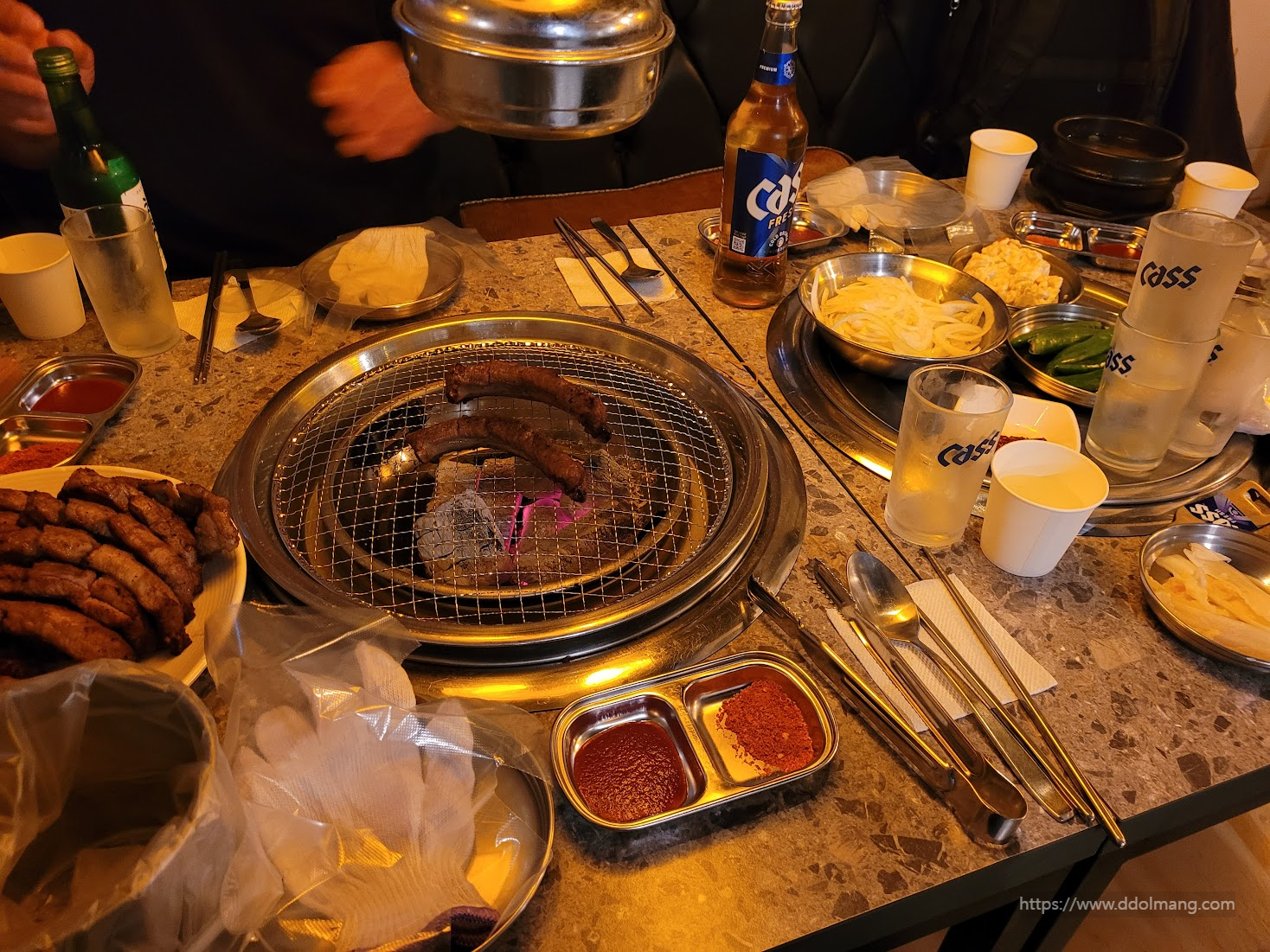 숯불 불판 위 구이 곱창, 소주, 맥주, 곁들임 반찬.