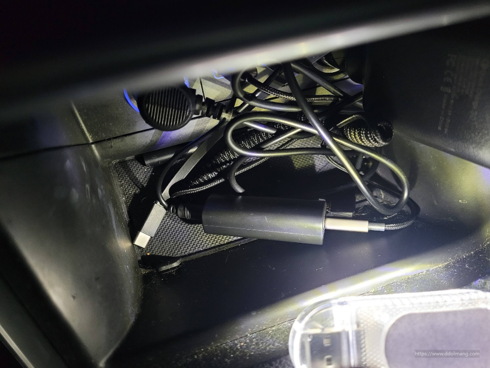 검은색 엉킨 케이블, USB-C 어댑터, 어두운 수납함 속 전자 기기