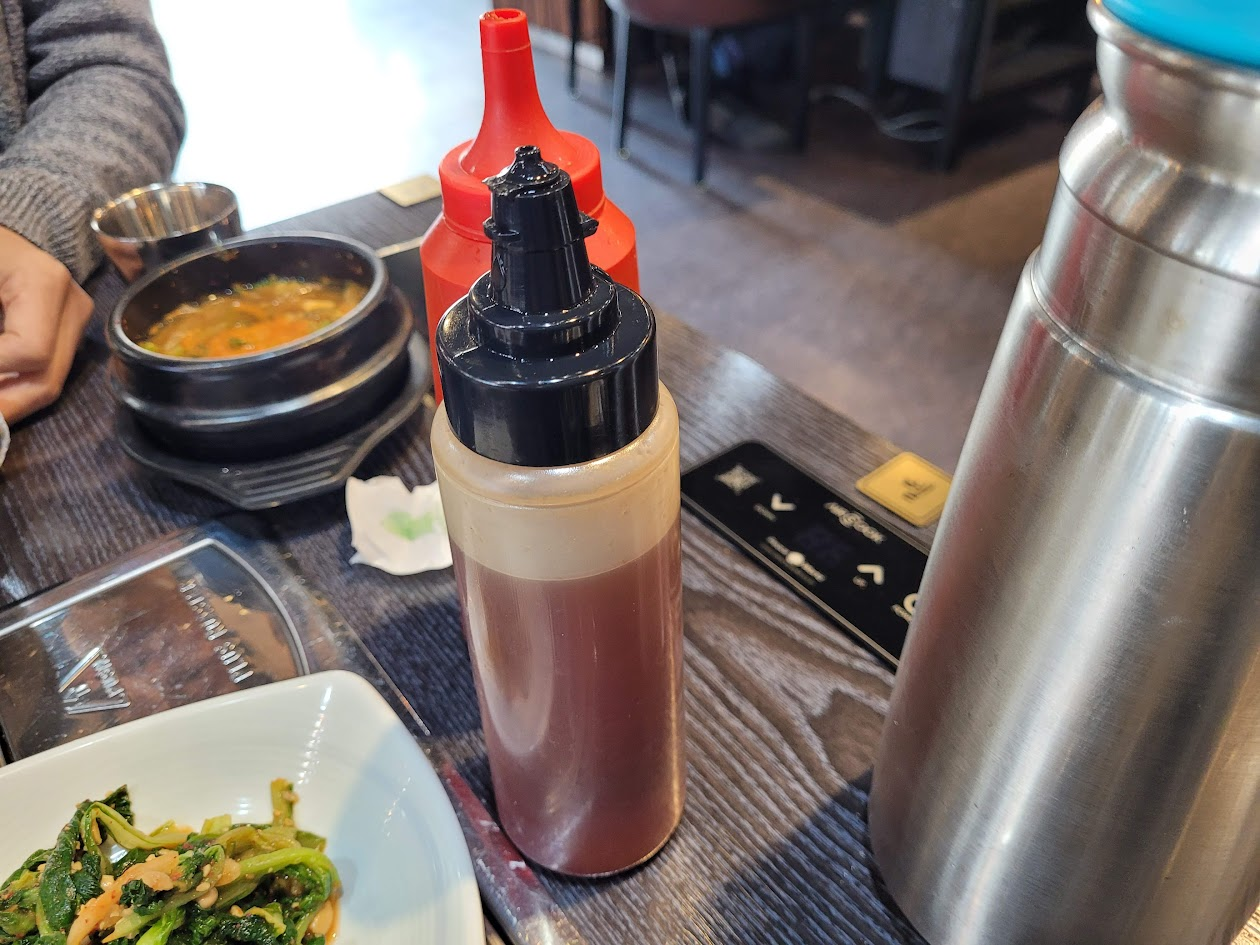 갈색 소스병, 빨간 소스병, 찌개, 반찬, 스테인리스 물통, 식탁 위