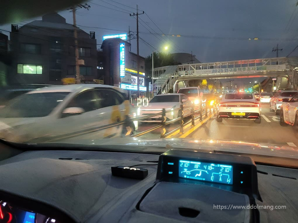 차량 내부에서 본 어스름 도시 도로, 정체 차량, 대시보드 디스플레이.