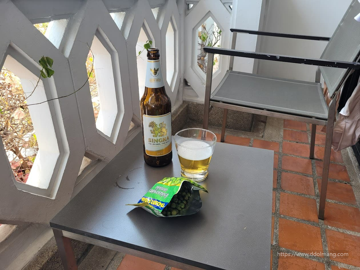 발코니 테이블 싱하 맥주병, 맥주잔, 녹색 완두콩 스낵