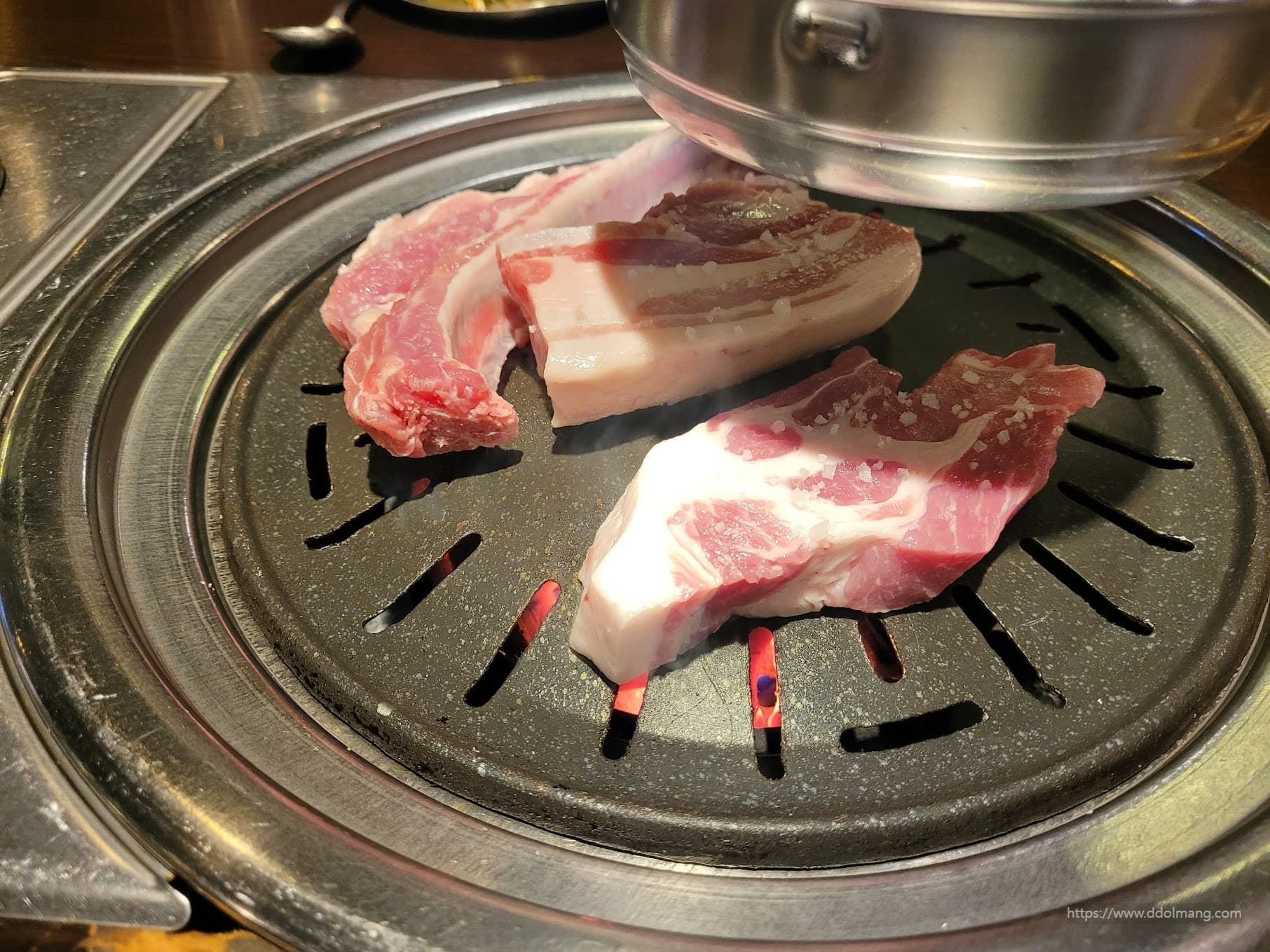 뜨거운 숯불 그릴 위 소금 뿌려진 두툼한 생삼겹살