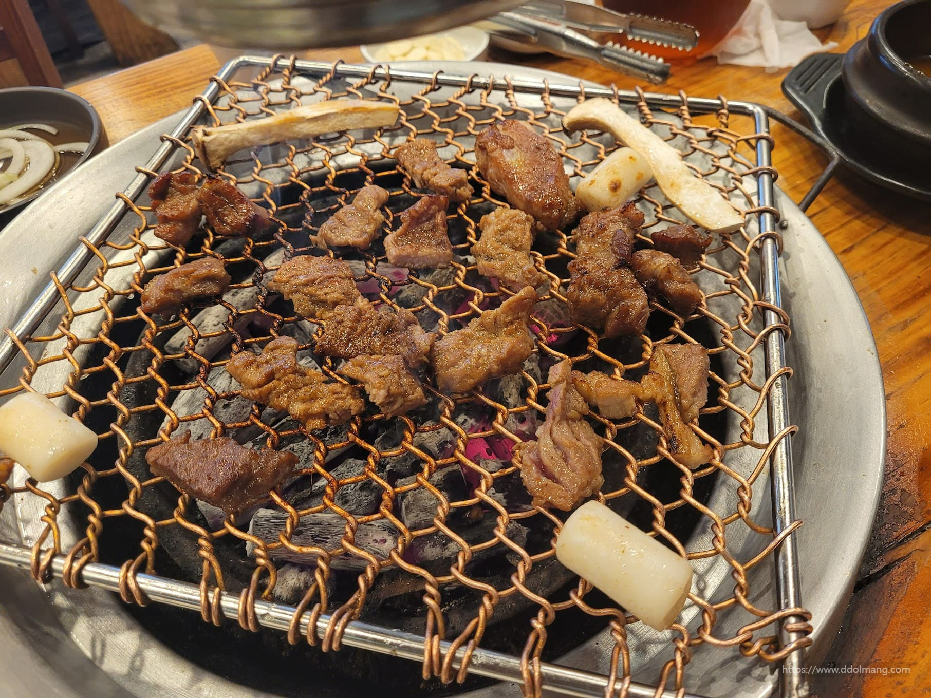 따뜻한 숯불 석쇠 위 노릇하게 구워지는 갈비, 떡, 버섯
