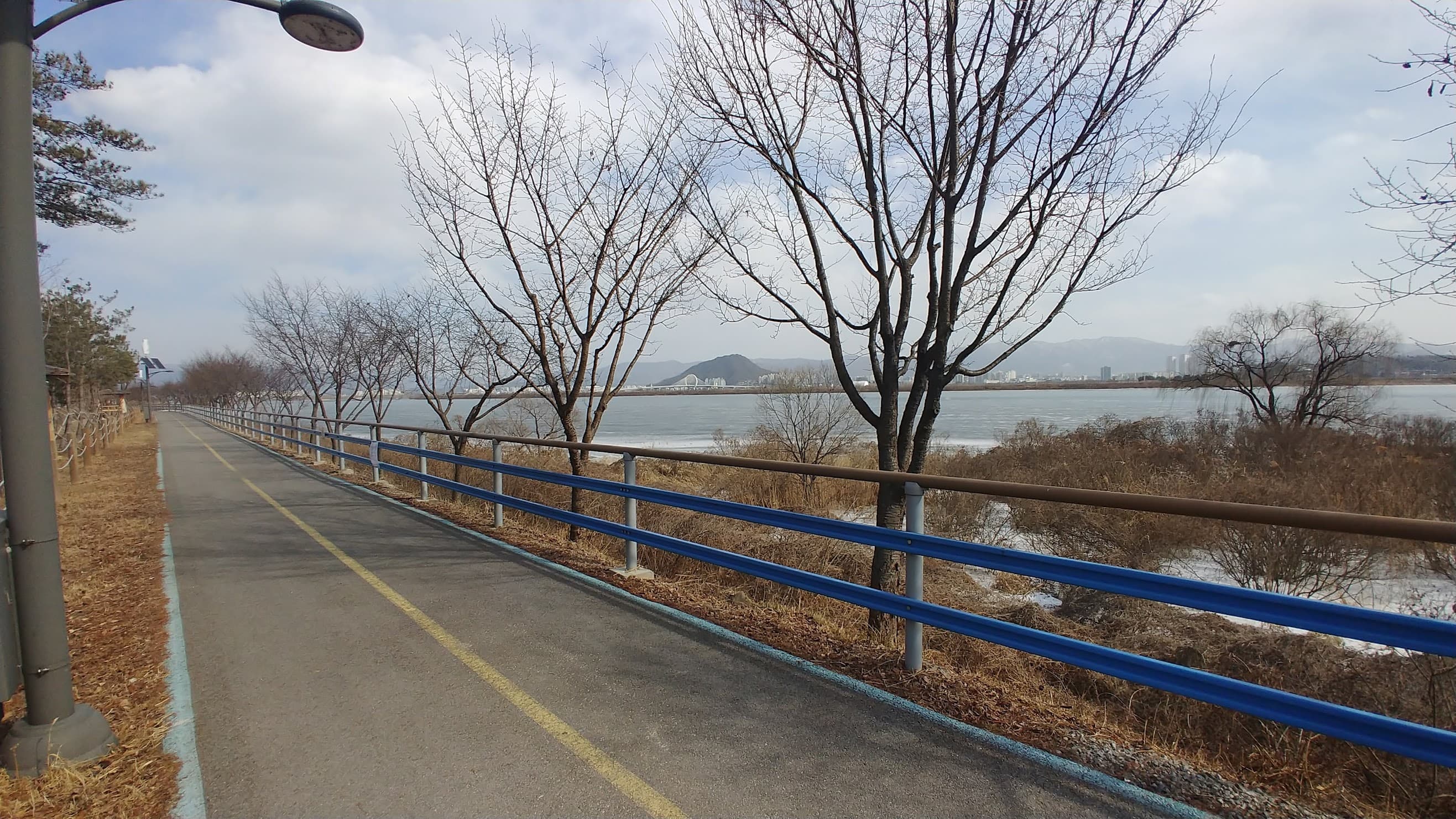 겨울 강변 자전거 도로, 앙상한 나무, 얼어붙은 강물, 파란 난간