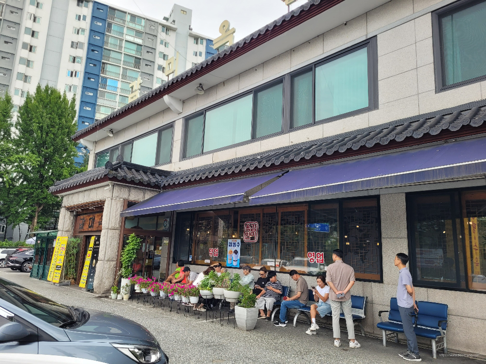 전통 한옥 건물, 파란색 어닝, 야외 좌석, 화분, 도심 아파트 배경
