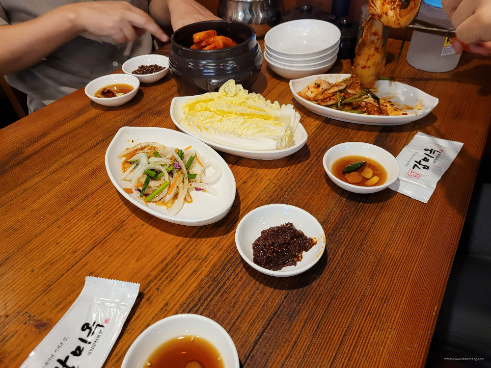 나무 식탁 위 김치, 파절이, 다양한 한식 반찬