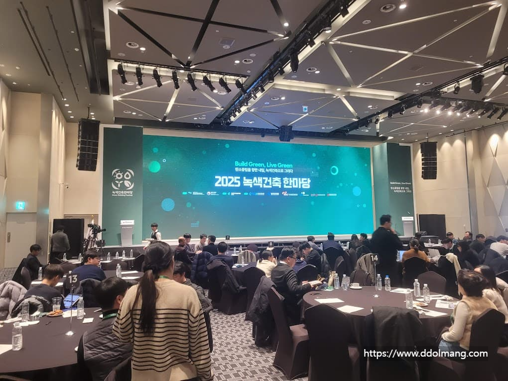 컨퍼런스 행사장, "2025 녹색건축 한마당" 대형 스크린, 테이블들