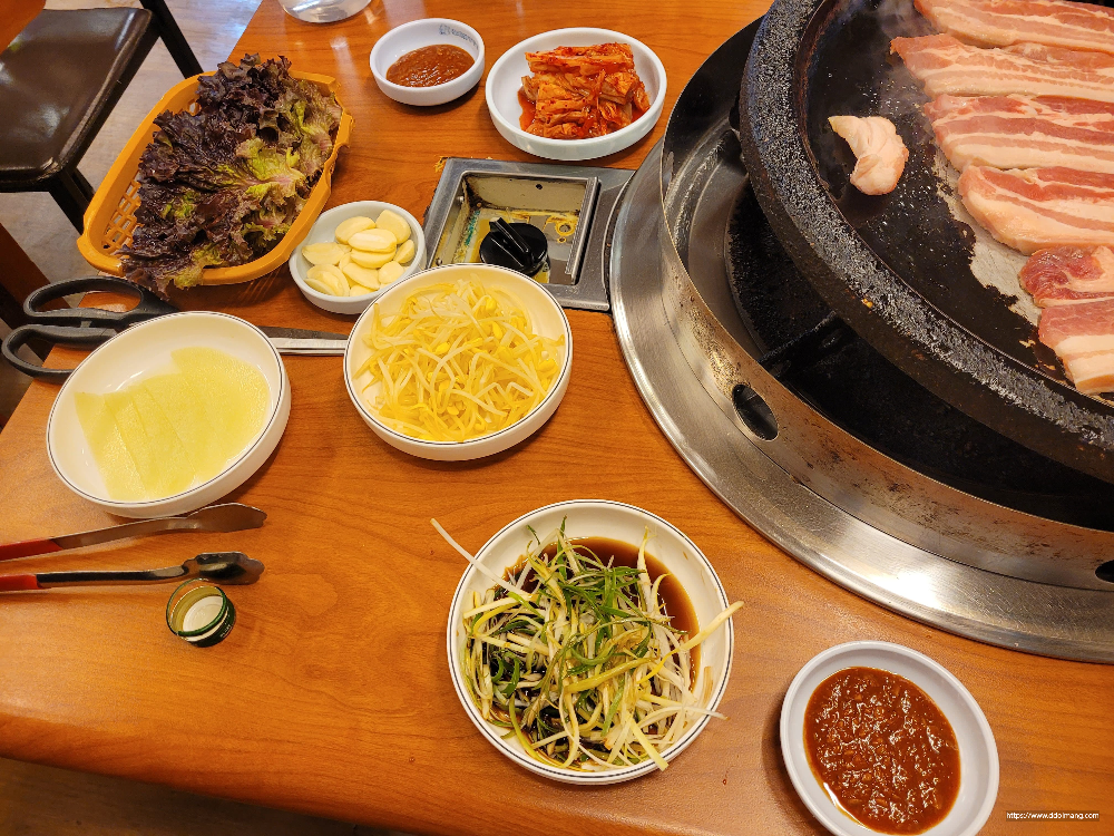 불판 위 삼겹살, 상추, 마늘, 김치, 파채, 숙주나물, 쌈무