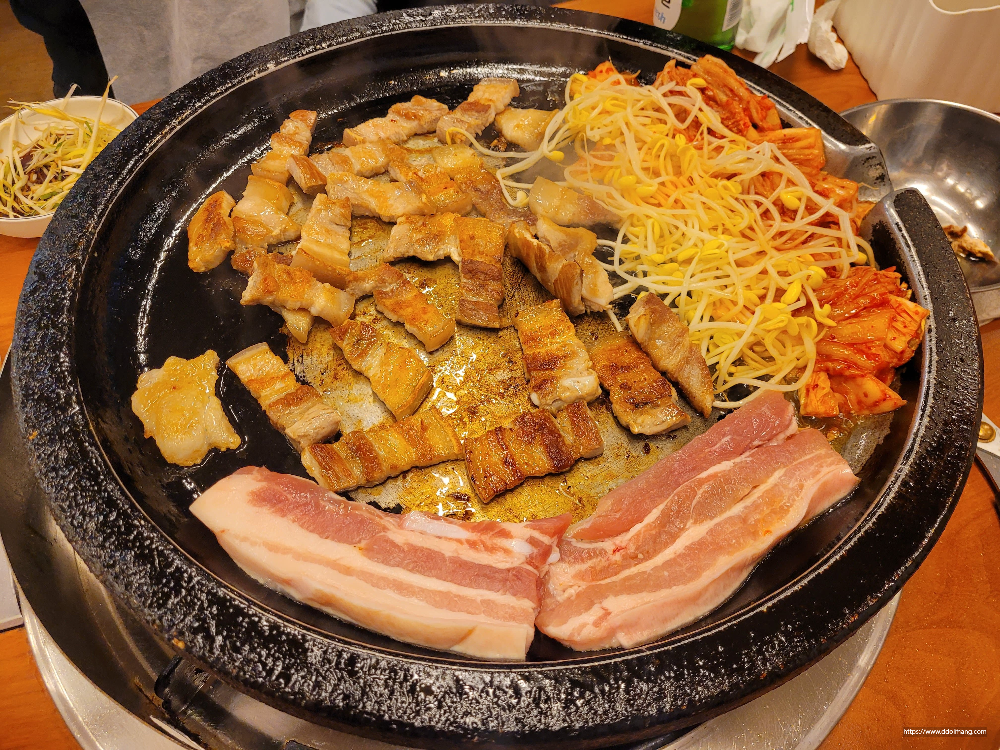 지글거리는 불판 위 삼겹살, 김치, 콩나물 구이