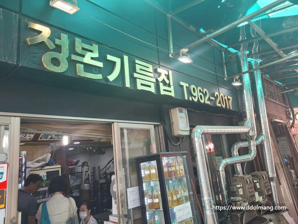 정본기름집 녹색 간판, 금색 글자, 진열된 기름병, 기계 설비