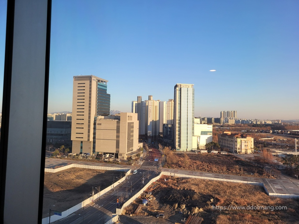 햇살 비치는 도심 고층 빌딩, 공터, 맑은 겨울 하늘.