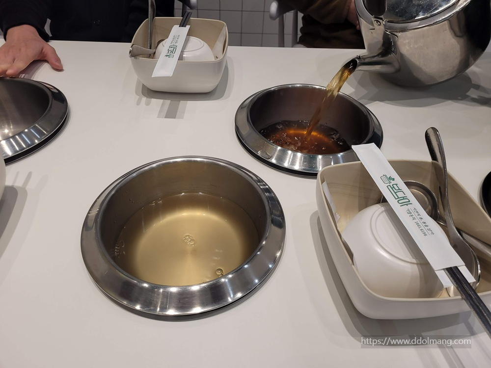 샤브샤브 냄비에 주전자 육수 붓는 식당 테이블.