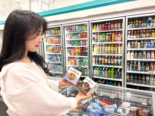 편의점 음료 냉장고 앞 아이스 브륄레 디저트 두 개 들고 있는 손