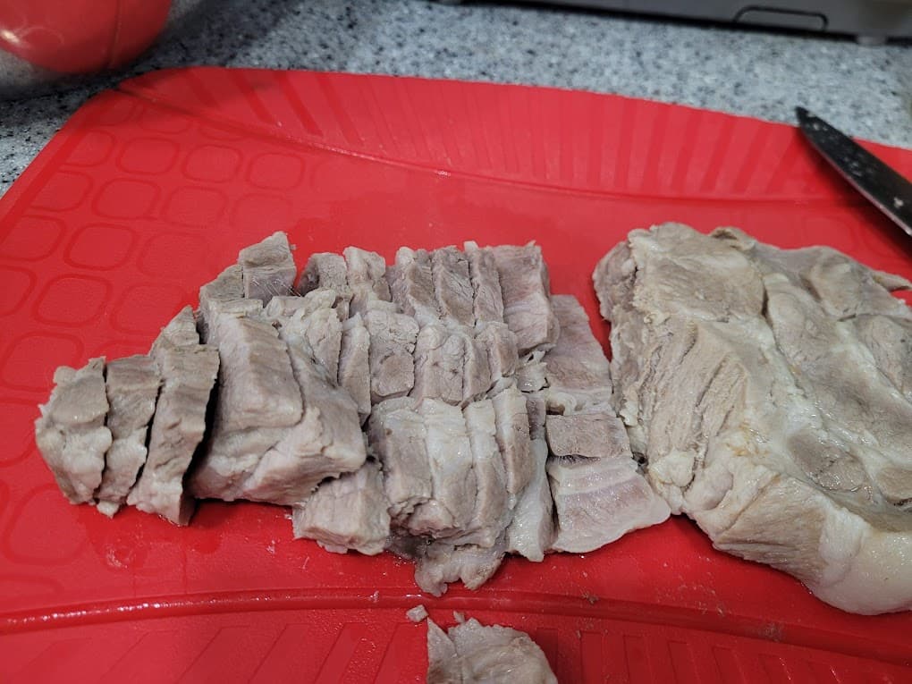 빨간 도마 위 큼지막하게 썰린 부드러운 돼지고기 수육