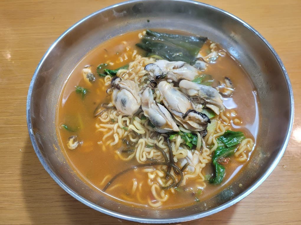 스테인리스 그릇에 굴 라면, 매콤한 국물과 해초