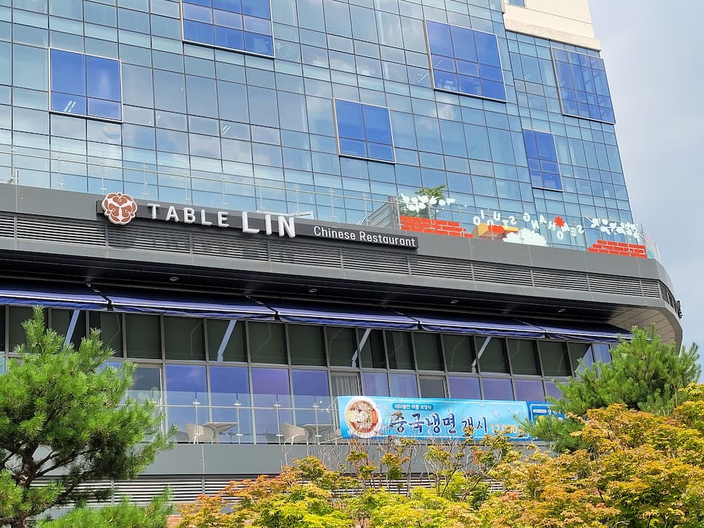 유리 외벽 중식당, TABLE LIN 간판, 파란 차양, 푸른 나무