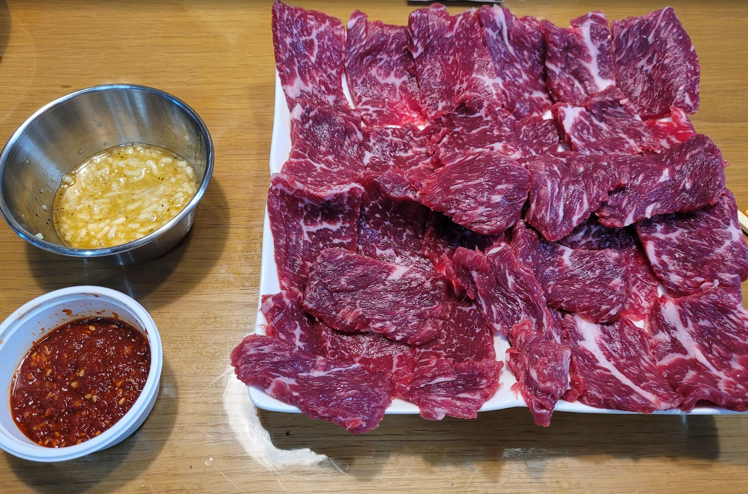 신선한 마블링 소갈비살, 마늘 기름장, 매콤한 쌈장 소스
