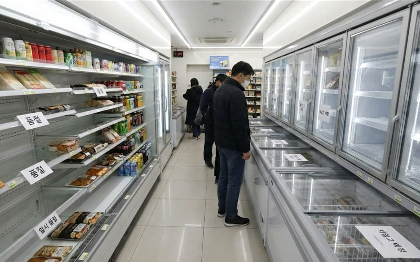 편의점 텅 빈 진열대와 냉동고, 품절 재입고 예정 알림.