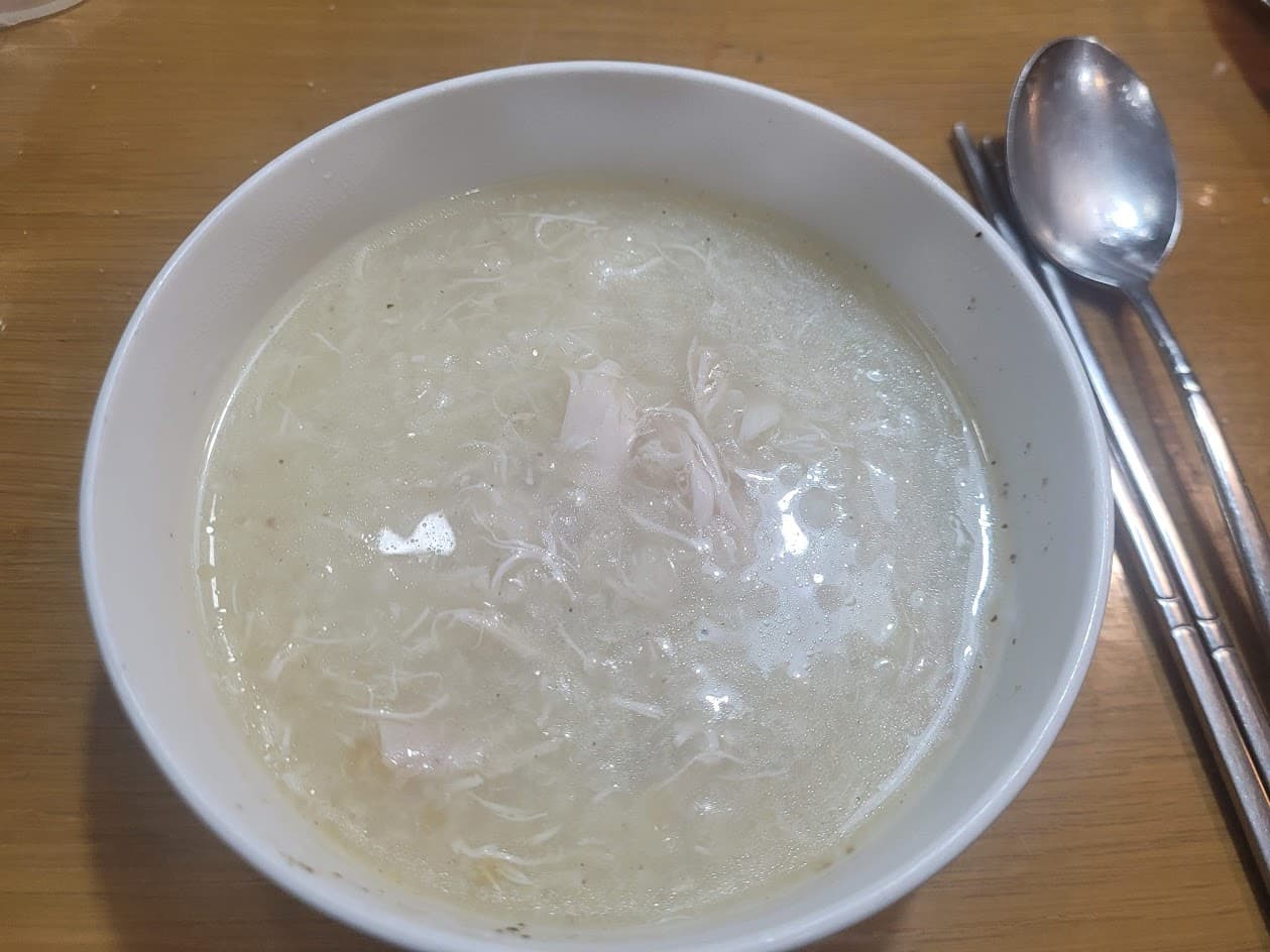 하얀 그릇 따뜻한 뽀얀 닭곰탕, 찢은 닭고기, 은색 수저