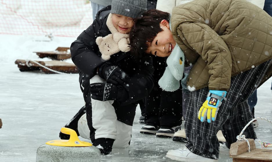 눈 내리는 얼음 위, 웃으며 겨울 컬링 즐기는 아이들