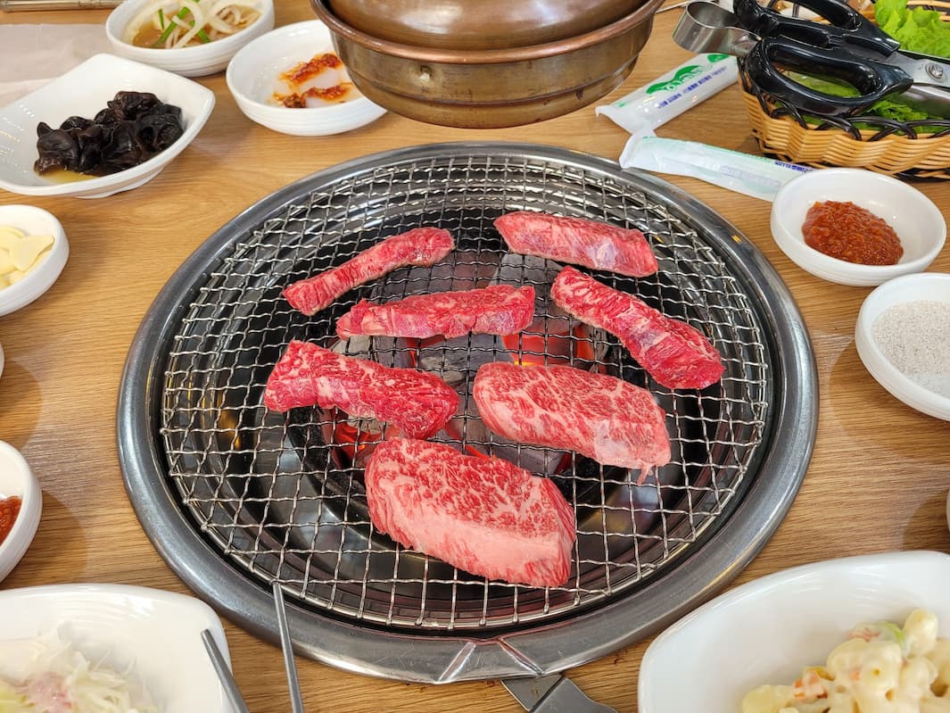 숯불구이 불판 위 마블링 소고기, 주변 한식 반찬