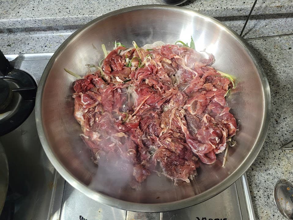 스토브 위 대형 그릇, 김나는 불고기 양념육, 파와 함께
