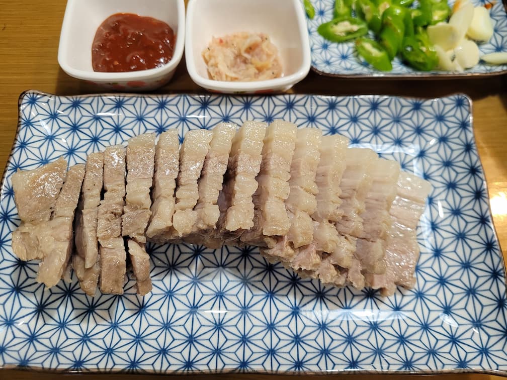 전통 한식 보쌈, 쌈장, 새우젓, 신선한 고추, 마늘