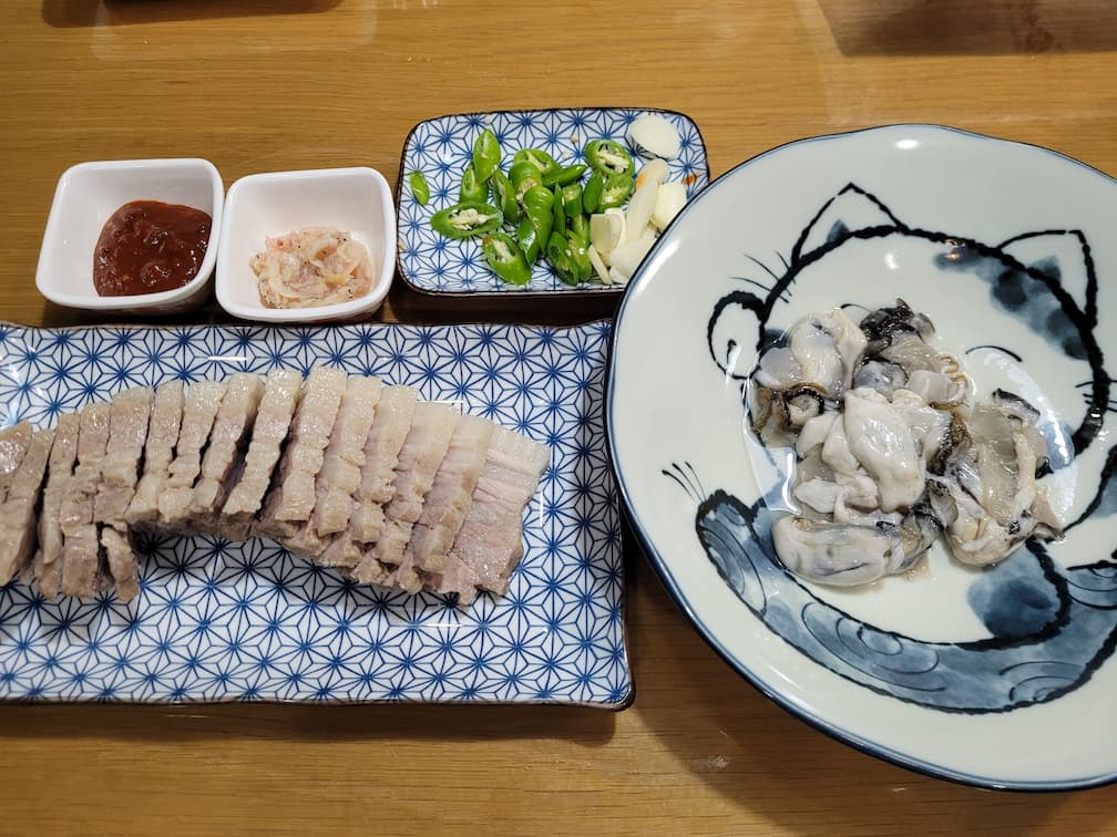 보쌈, 신선한 굴, 새우젓, 고추, 마늘 곁들인 한식 상차림