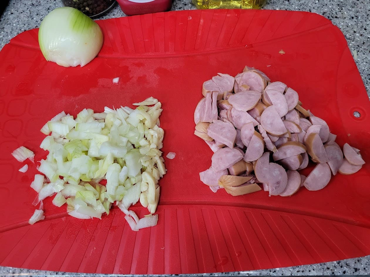 빨간 도마 위 다진 양파, 마늘, 썰린 소시지