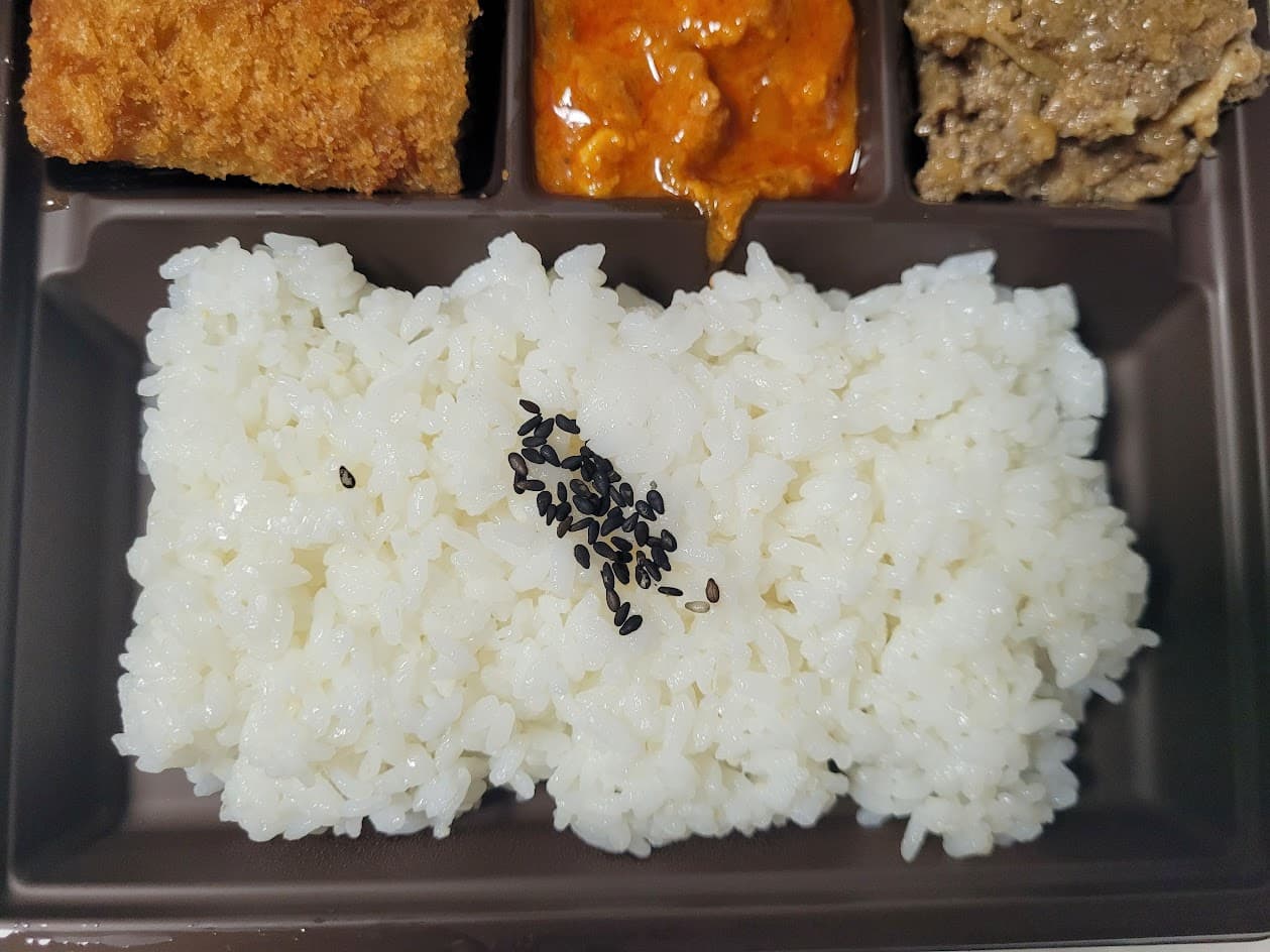 갈색 도시락 용기 속 흰밥, 검은깨, 돈까스, 매콤 반찬, 고기 반찬