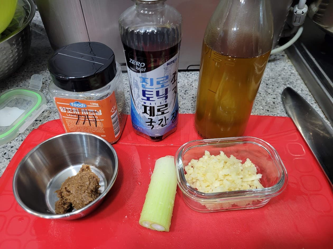 빨간 도마 위 된장, 다진 마늘, 대파, 조미료, 음료수병