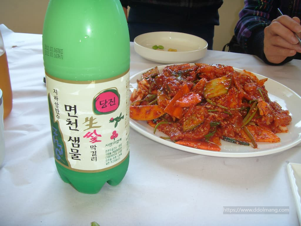 면천 샘물 막걸리 병, 매콤한 채소 볶음 테이블 위