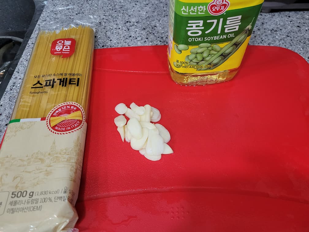 스파게티 면, 껍질 벗긴 마늘, 콩기름 빨간 도마 위.