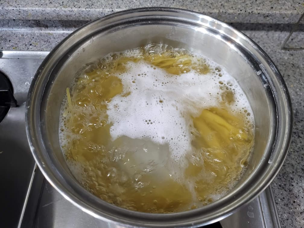 끓는 물 거품 속 스테인리스 냄비 노란 파스타 면