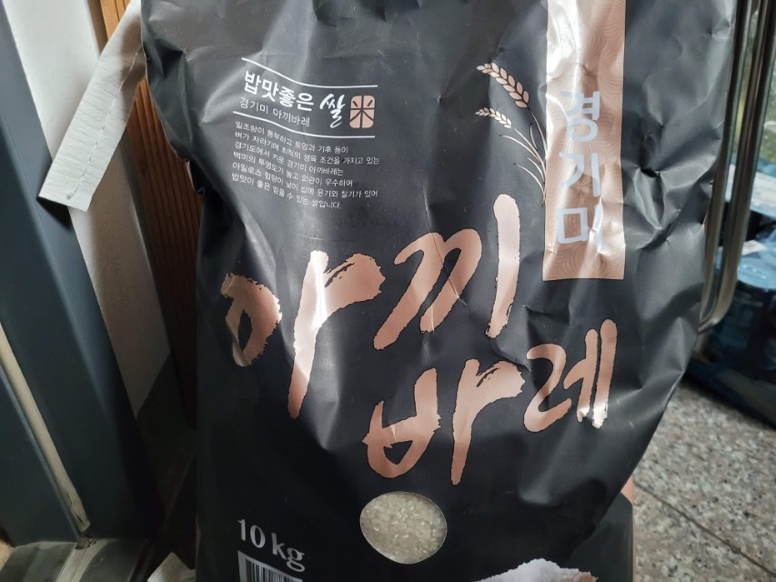 검은 경기미 아끼바레 쌀 포대, 10kg, 흰 쌀알 노출.