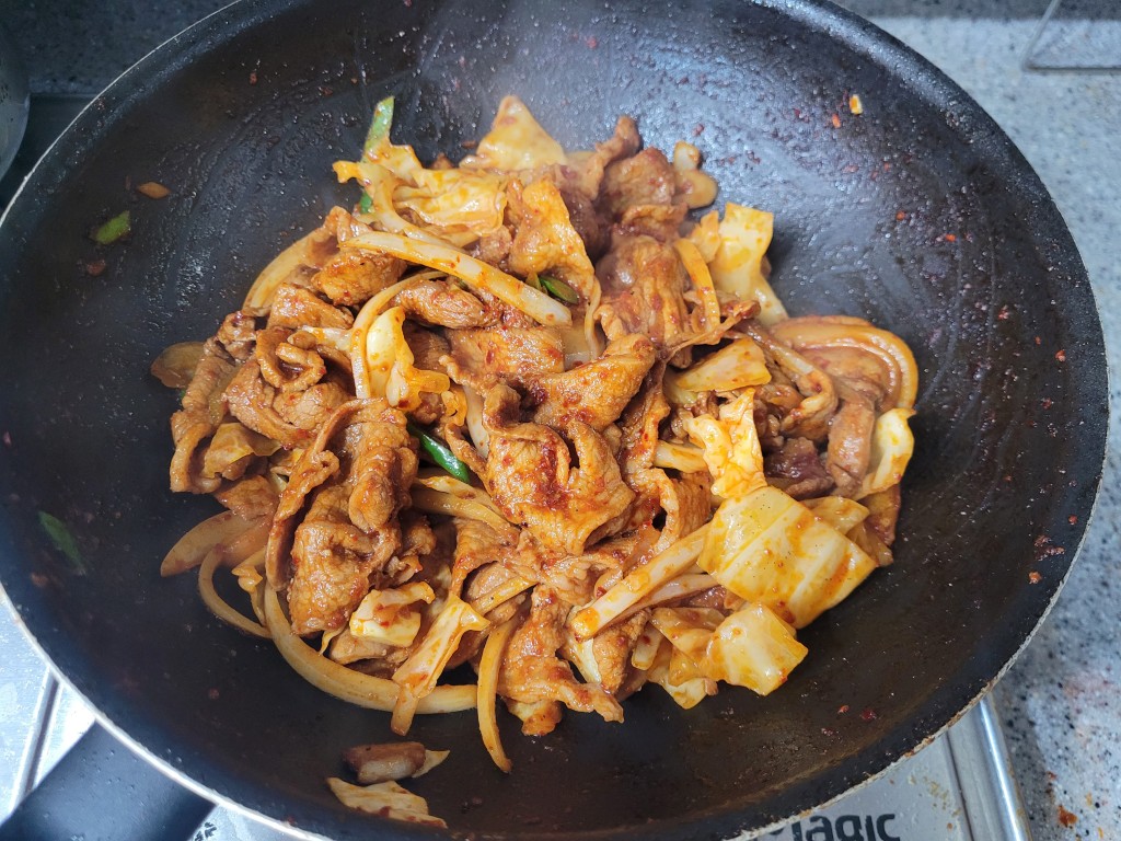 검은 팬 속 매콤한 돼지고기 양배추 양파 볶음