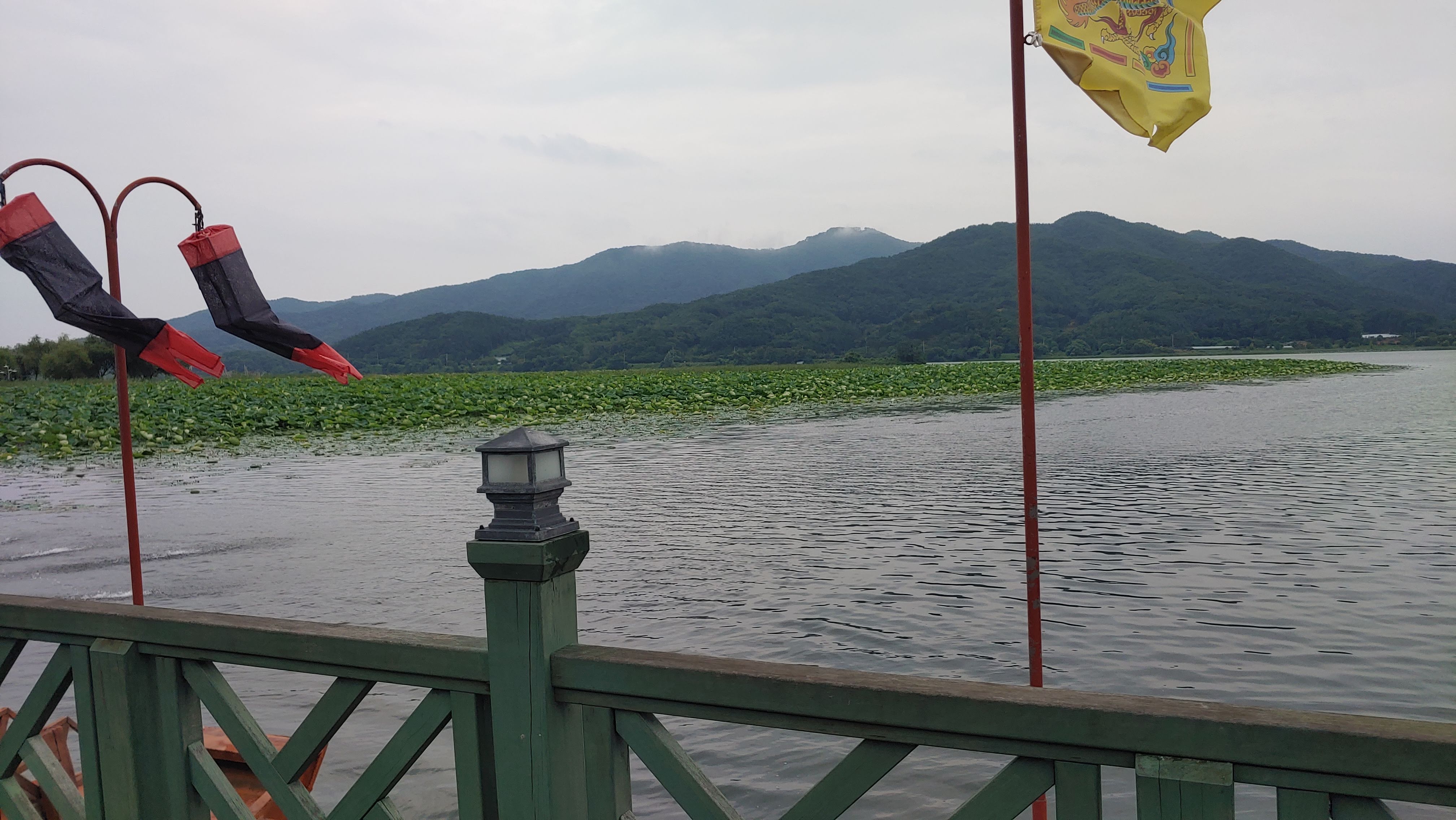 연잎 호수, 푸른 산 배경, 난간, 전통 깃발 장식
