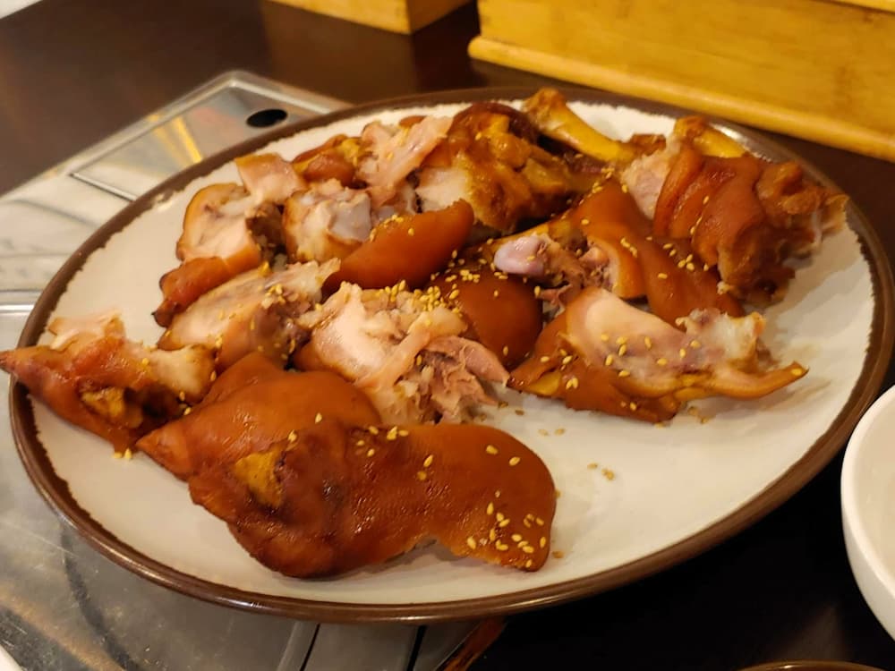 윤기 나는 썰린 족발, 깨 뿌려진 먹음직스러운 한식.