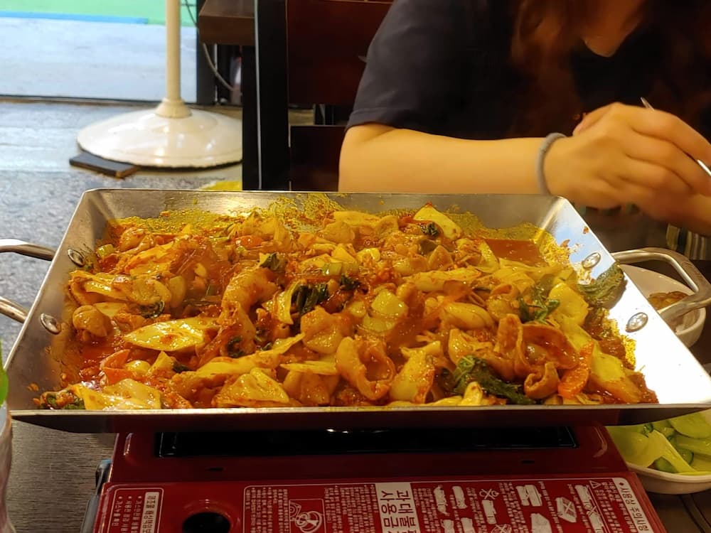 식당 테이블 위, 지글거리는 매콤한 곱창볶음과 채소