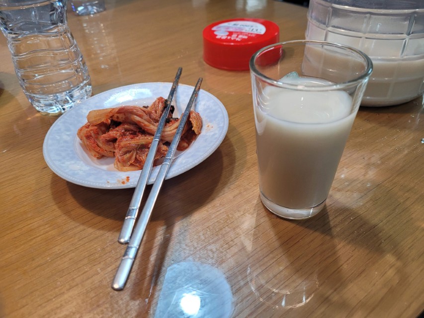 나무 탁자 위 매콤한 김치, 젓가락, 막걸리 잔