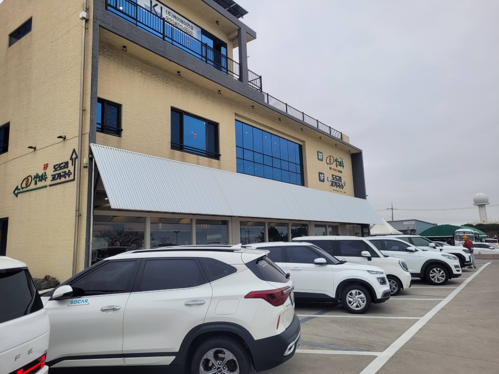 노란 건물 앞 주차된 흰색 차량들, 식당 간판 명확히 보임.