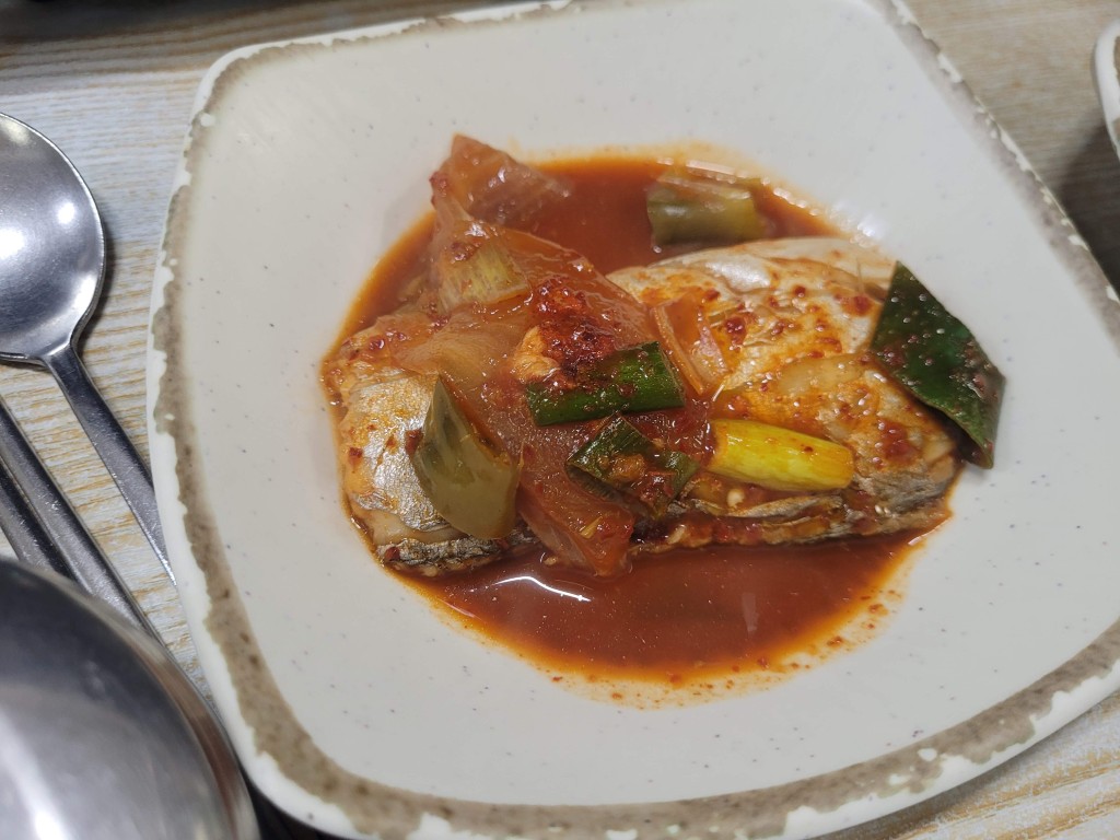 하얀 접시에 담긴 매콤한 갈치조림, 큼직한 대파와 양파