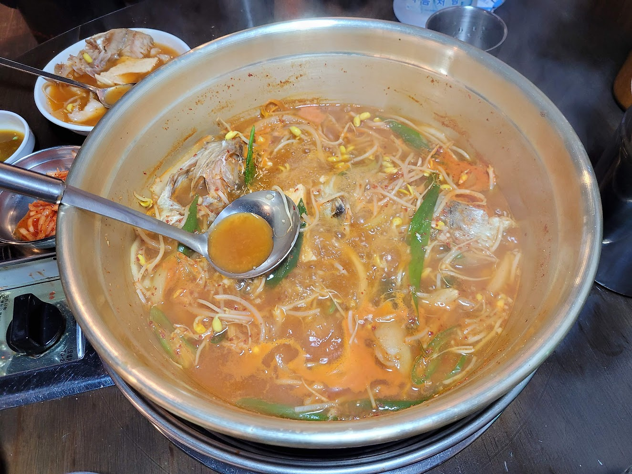 끓는 얼큰한 매운탕, 국자로 국물 뜨는, 생선, 콩나물