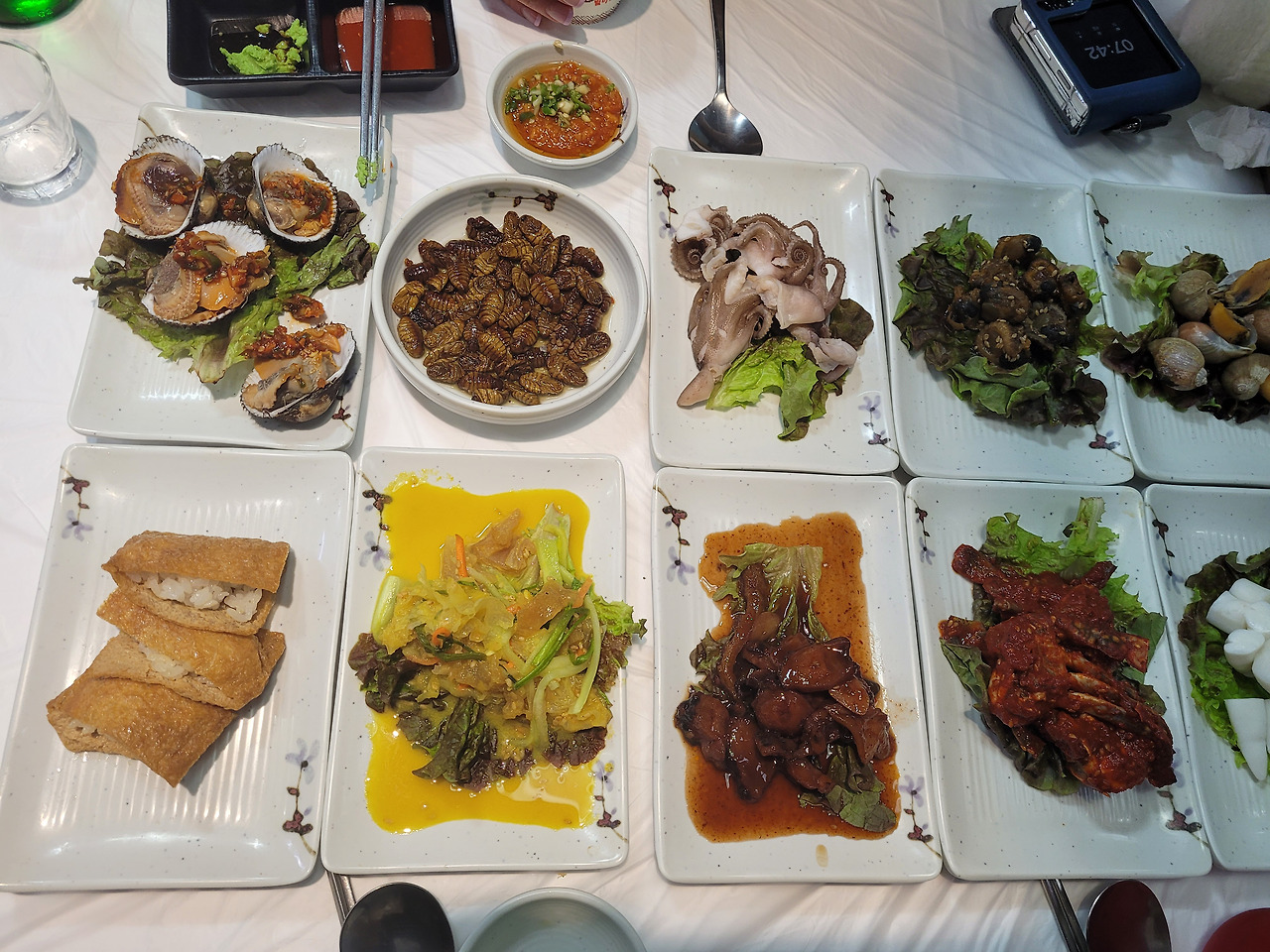 여러 한식 해산물 반찬, 번데기, 유부초밥, 채소 요리 상차림