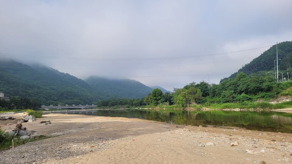 안개 덮인 산, 고요한 강, 넓은 모래 강변, 멀리 다리