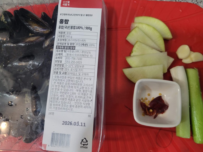 포장 홍합, 썰린 무, 마늘, 대파, 건고추, 빨간 도마