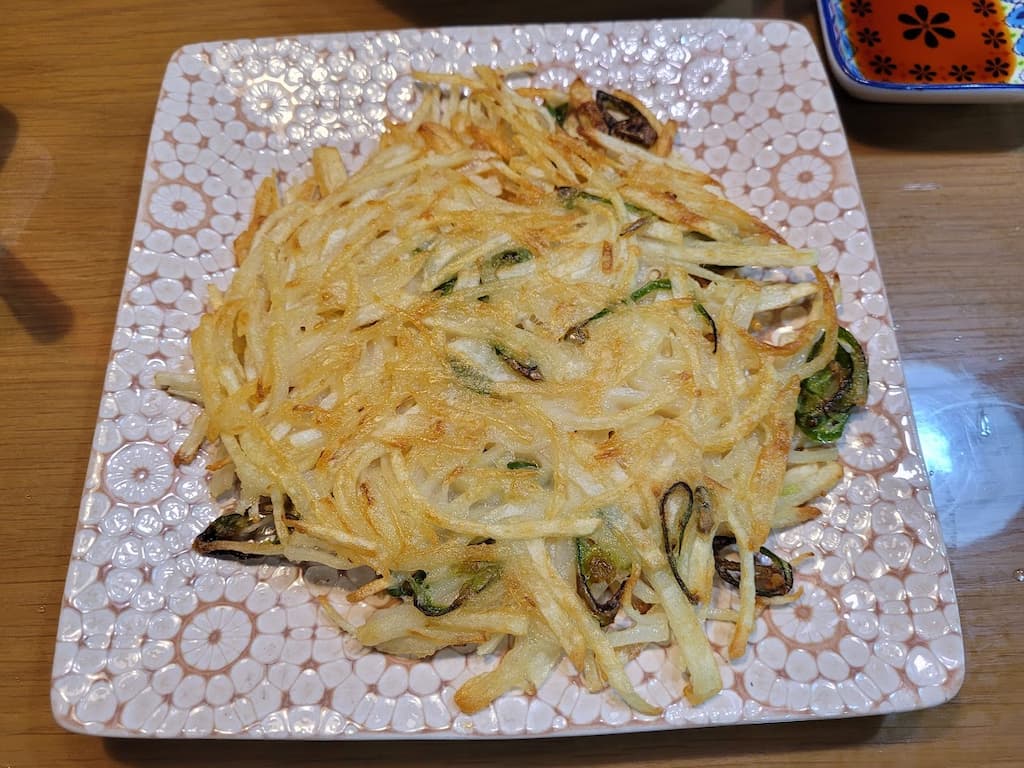 바삭하고 노릇한 채 썬 감자전, 무늬 접시 위