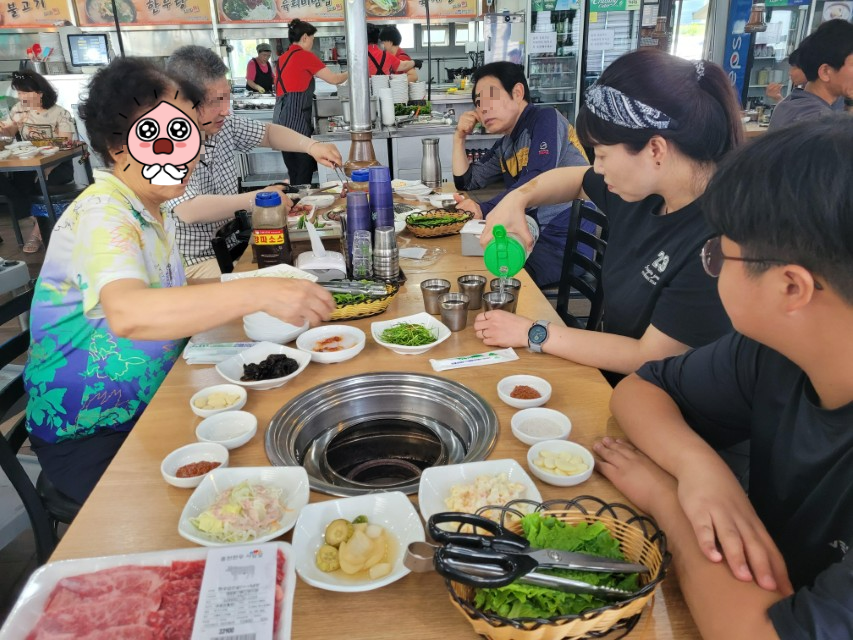 불판과 다양한 반찬, 신선한 고기, 물 따르는 식탁