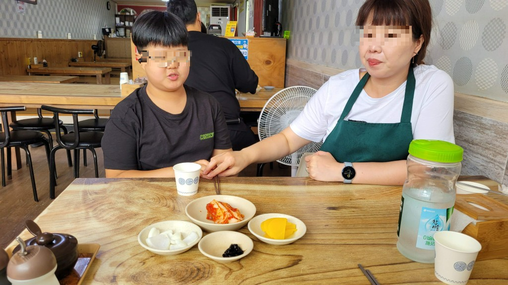 식당 나무 테이블, 김치 단무지 반찬들, 오순도순 식사 시간