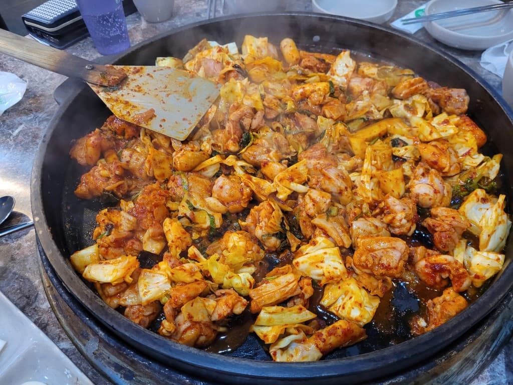 매콤한 닭갈비 닭고기 양배추 큰 팬에서 조리. 주걱.